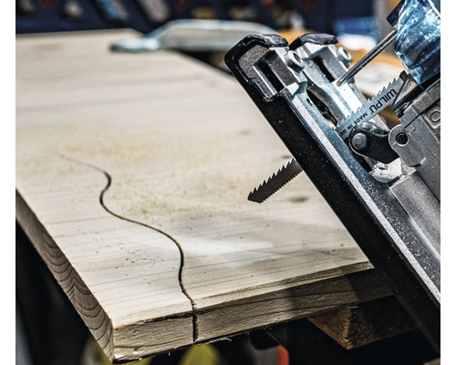 Detailný záber priamočiarej píly reže zakrivený vzor do drevenej dosky