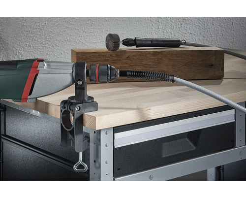 Vŕtací stroj s namontovaným ohybným hriadeľom a stolovou svorkou na pracovnom stole.