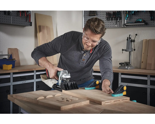 Muž používa kolíkovač v dielni na obrábanie drevených dielov.