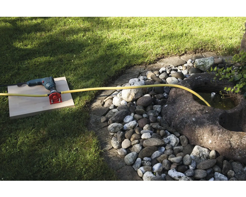 Vŕtačka s pripojením na vodu a hadicou v záhrade.