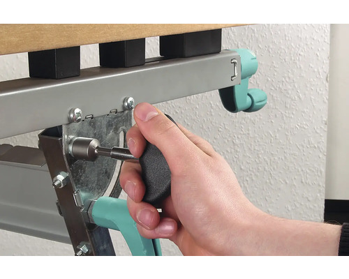 Osoba pripevňuje skrutku skrutkovačom k rámu kovovej postele.