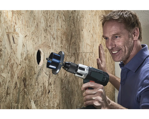 Muž vŕta dierovkou otvor do drevenej steny.