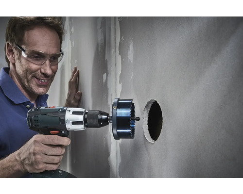 Remeselník vŕta otvor do steny pomocou dierovky