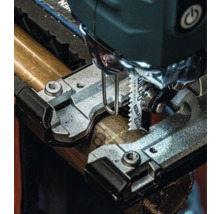 Detailný pohľad na priamočiaru pílu reznúcu kovovú rúrku.