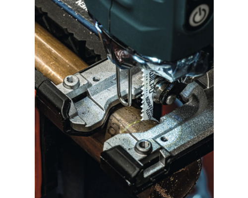 Detailný pohľad na priamočiaru pílu reznúcu kovovú rúrku.