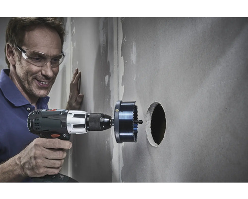 Muž vŕta otvor do steny pomocou dierovacej píly