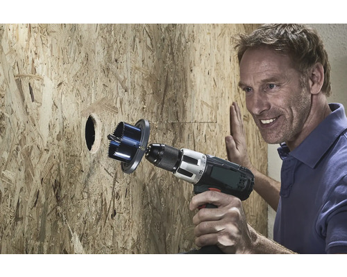 Muž vŕta otvor do drevenej dosky pomocou dierovky.