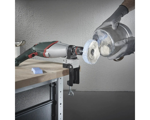 Vŕtačka s leštiacim nástavcom a zverákom na pracovnom stole leští kovovú vedro