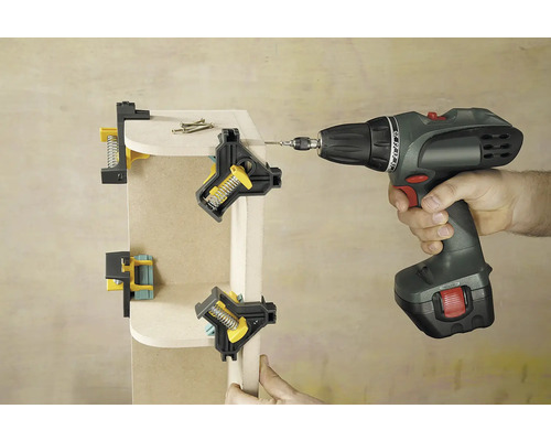 Dielenská scéna zobrazuje drevený roh upevnený uhlovými svorkami a zoskrutkovaný akumulátorovým skrutkovačom.