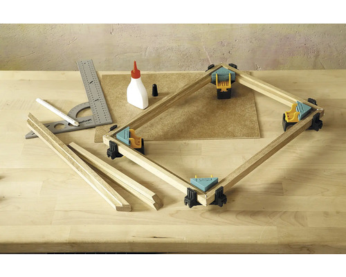 Pracovný stôl s pokosovou svorkou, drevené lamely, uholník, ceruzka a fľaša lepidla na spracovanie dreva