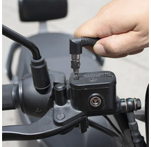 Osoba používa skrutkovač s uhlovým nástavcom na prácu na motocykli.