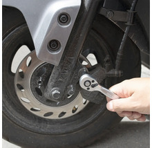 Osoba používa račňu na motocykli.