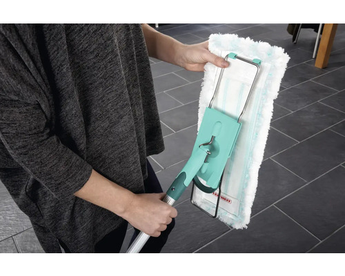 Osoba drží mop s umývateľným návlekom. Mop má teleskopickú tyč a otočnú hlavicu na čistenie podláh.