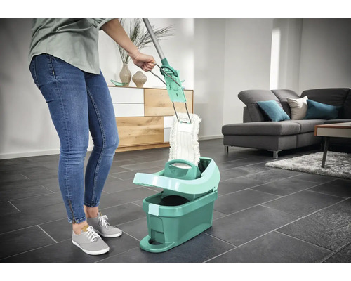 Žena používa mop s vedrom v obývacej izbe na čistenie podláh