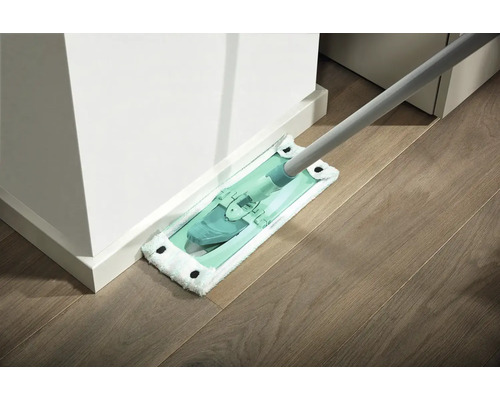 Mop s návlekom z mikrovlákna čistí drevenú podlahu pri bielej stene.