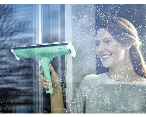 Žena čistí okná stierkou na okná