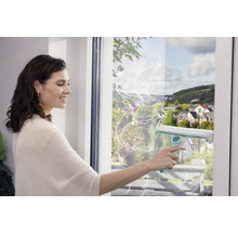 Žena čistí okná stierkou pre čistenie bez šmúh