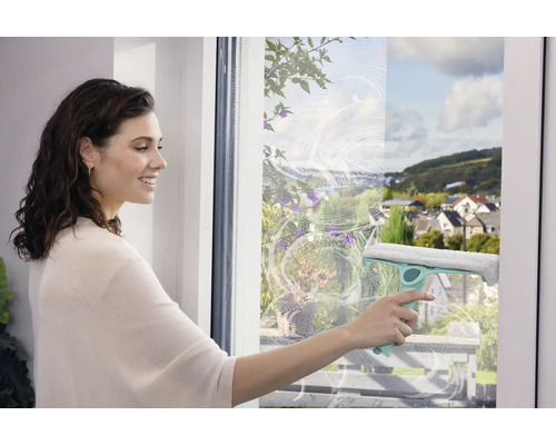 Žena čistí okná stierkou pre čistenie bez šmúh