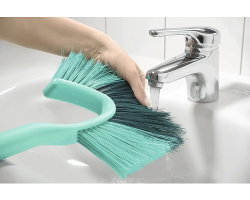 Ruka pod kohútikom oplachuje kefu v umývadle