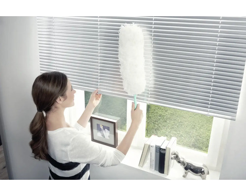 Žena čistí žalúzie prachovkou