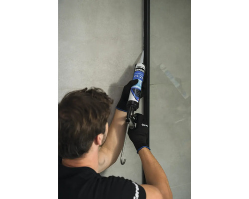 Remeselník používa silikónovú pištoľ pre sanitárnu oblasť.