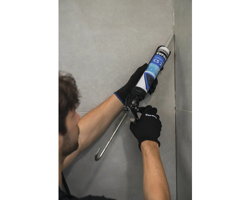 Remeselník nanáša tmel na škáru dlaždice