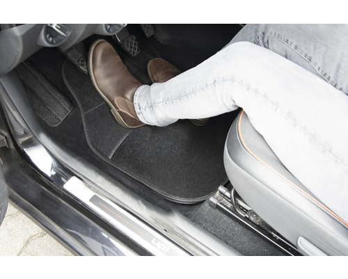 Interiér vozidla s podlahovou rohožou a nohou na pedáli