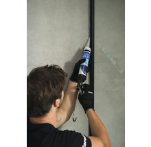 Remeselník utesňuje sprchovú stenu silikónom. Viditeľné logo Ceresit.