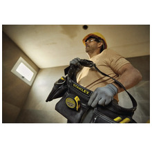 Remeselník s brašnou na náradie Stanley a zvinovacím metrom na stavenisku