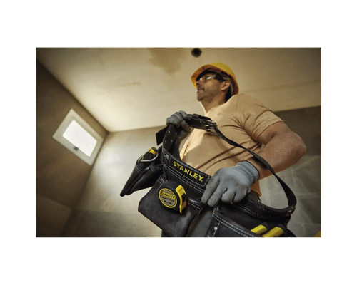 Remeselník s brašnou na náradie Stanley a zvinovacím metrom na stavenisku