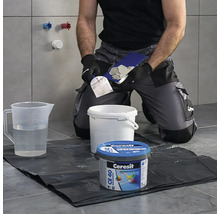 Obkladač pripravuje škárovaciu hmotu s náradím a škárovacou hmotou Ceresit CE 40 Premium