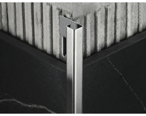 Detailný záber kovovej dlaždicovej lišty v rohu medzi dvoma dlaždicami