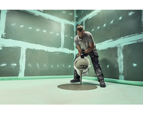 Remeselník leje vyrovnávaciu hmotu do kúpeľne s utesnenými stenami.