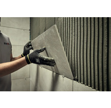 Dlaždič inštaluje obklad v kúpeľni