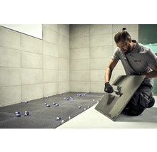 Obkladač pri práci, dlaždice, náradie a logo AkKit