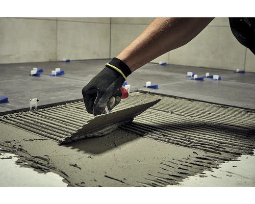 Obkladač s hladidlom nanáša lepidlo na dlaždici, aby ju položil