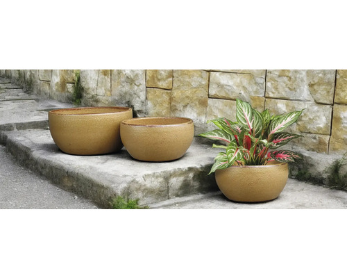 Tri okrúhle kvetináče na kamenných schodoch, jeden z nich s rastlinou