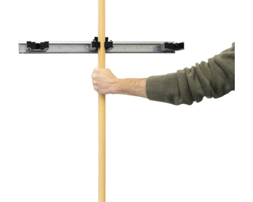 Muž upevňuje rukoväť do nástenného držiaka na náradie