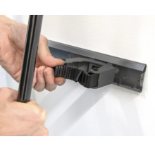 Osoba pripevňuje nástroj k lište držiaka nástrojov na stene.