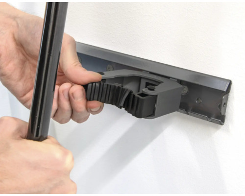 Osoba pripevňuje nástroj k lište držiaka nástrojov na stene.