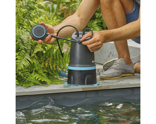 Muž obsluhuje jazierkové čerpadlo na okraji jazierka.