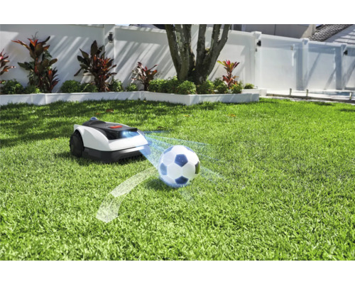 Robotická kosačka na trávniku s futbalovou loptou