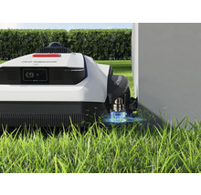 Robotická kosačka na trávniku blízko steny