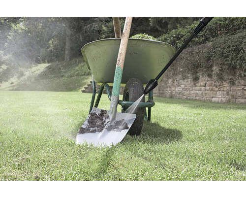 Čistenie rýľa vysokotlakovým čističom vedľa kolieska v záhrade