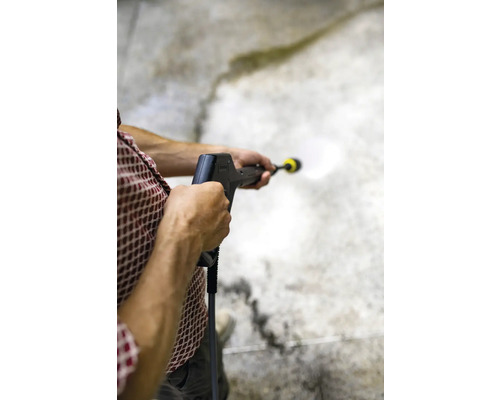 Osoba používa vysokotlakový čistič na čistenie povrchu.