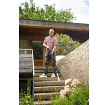 Muž čistí vonkajšie schodisko vysokotlakovým čističom.