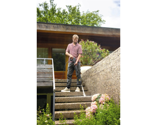 Muž čistí vonkajšie schodisko vysokotlakovým čističom.