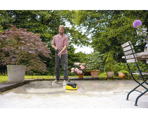 Muž čistí terasu čističom terás v záhrade.