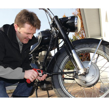 Muž opravuje motorku skrutkovačom