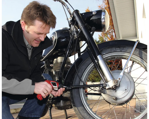 Muž opravuje motorku skrutkovačom